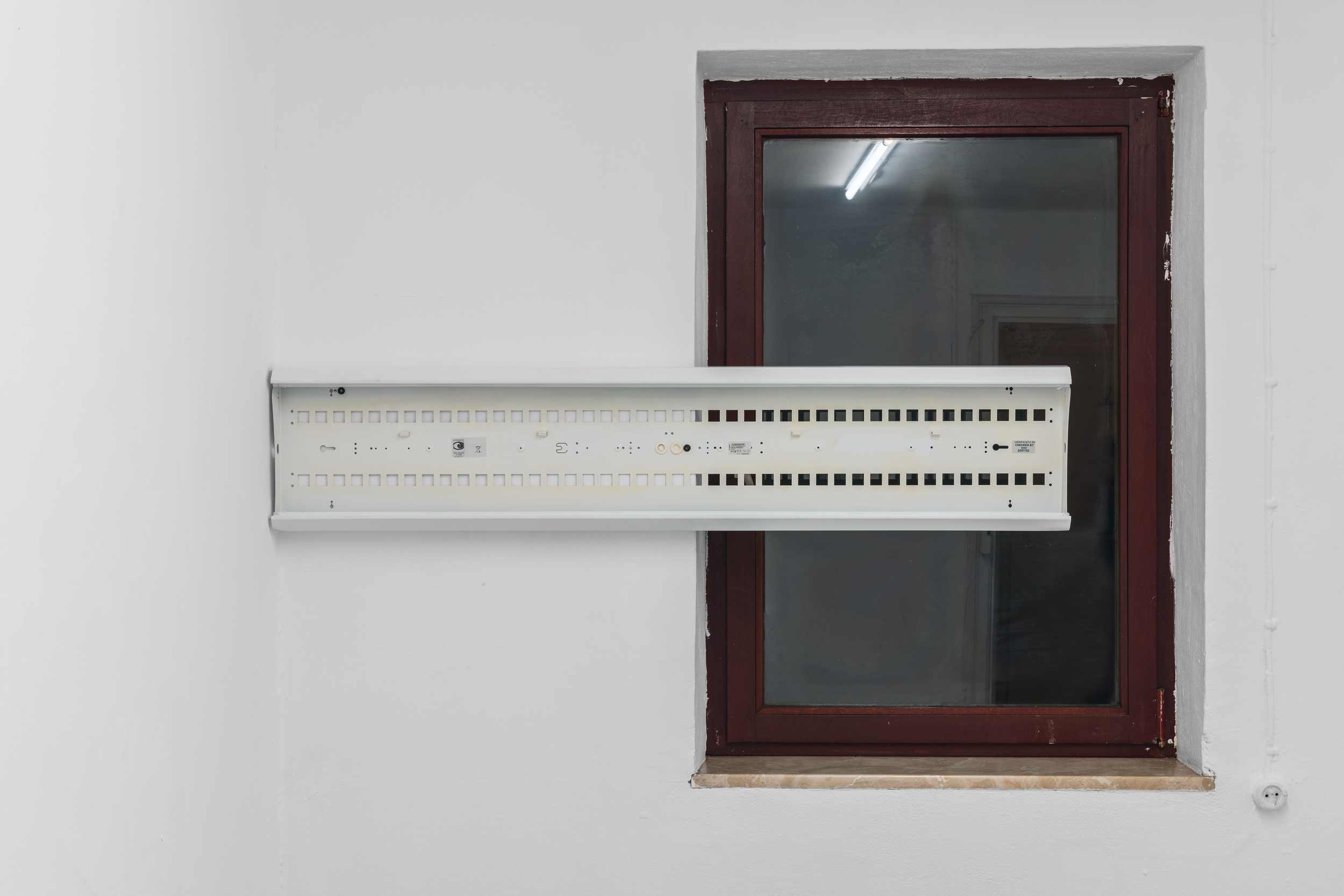 Aisha Altenhofen solo exhibition at Austin Space: Close up of one of the grid light fixtures installed over the brown gallery window.