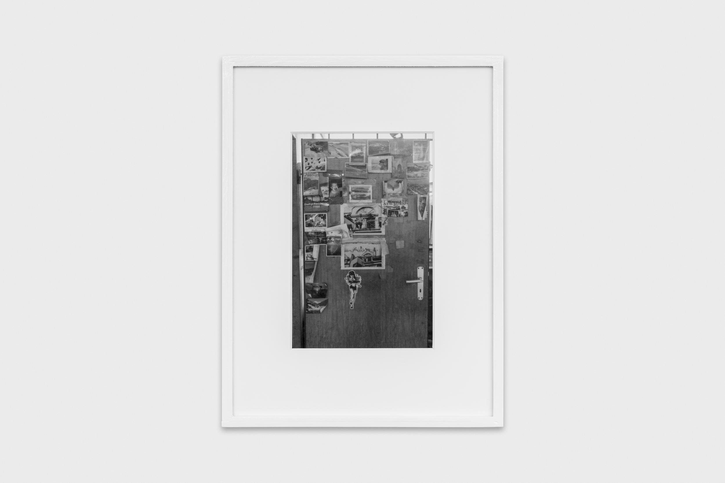Aisha Altenhofen solo exhibition at Austin Space: Black and white photograph of a door plastered with photographs, postcards and notes.