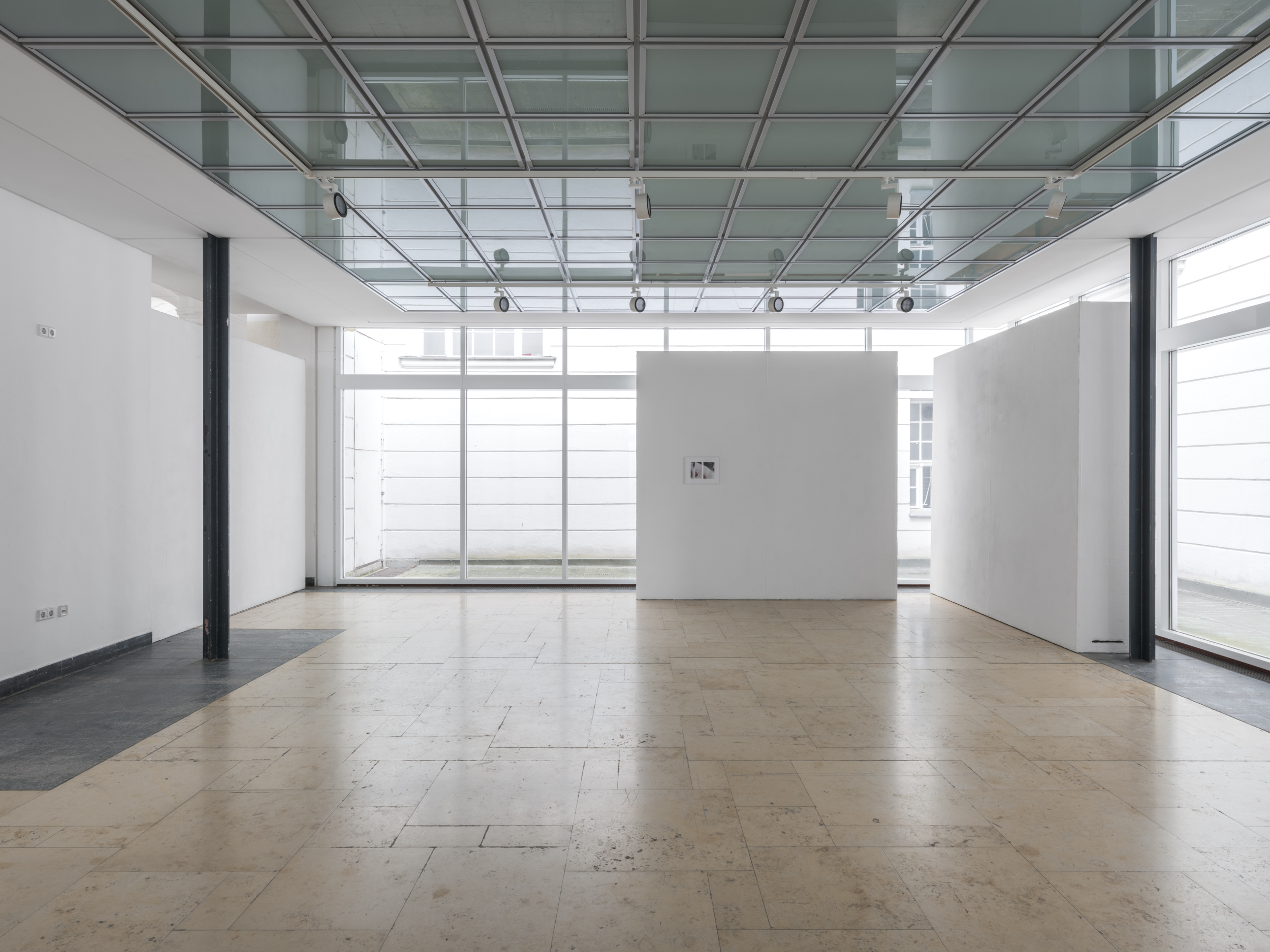 Aisha Altenhofen solo exhibition at Austin Space: Installation view of a minimal white gallery space with grey wooden floors, featuring small framed photographic works and a horizontal industrial light fixture mounted across a central window.
